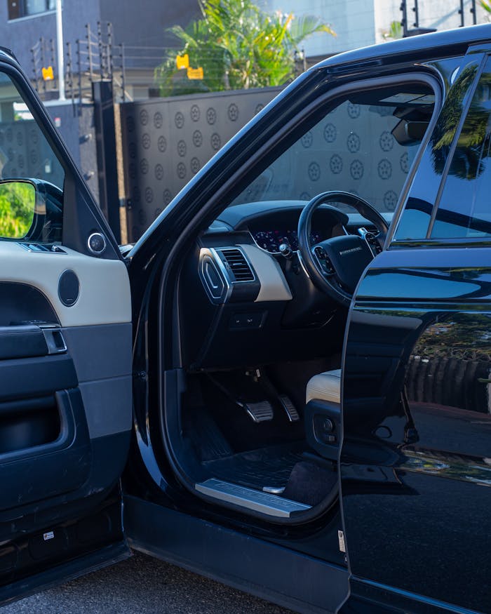 High-end black vehicle with an open door showcasing sleek interior design and exterior reflections.